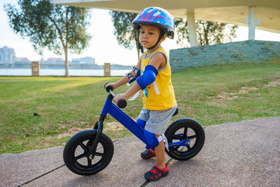 Cute boy riding bicycle on footpath at park