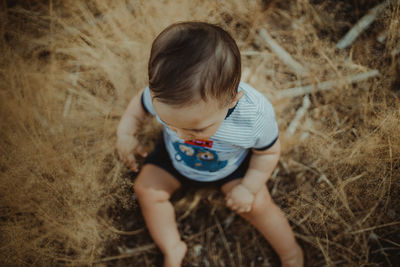 High angle view of cute baby boy sitting on grass