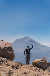 Rear view of man standing on mountain against sky