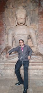 Full length of man standing by buddha statue