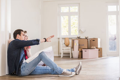 Young couple in new home sitting on floor discussing ground plan