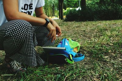 Low section of boy sitting on grass in field