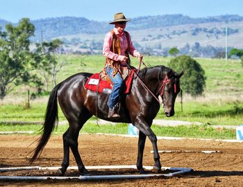 Woman riding horse on field