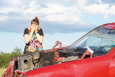 Rear view of woman sitting on car against sky