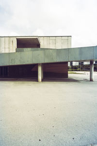 Empty road by building against sky