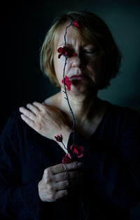 Woman holding red flowers against black background