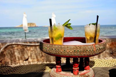 Close-up of beer on table at beach against sky