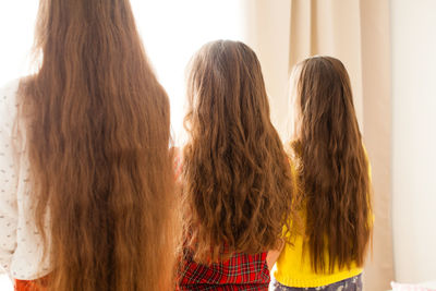 Rear view of women standing against wall