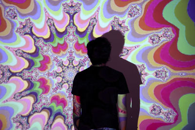 Rear view of silhouette man standing against multi colored wall