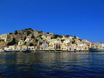 Scenic view of sea by town against clear blue sky