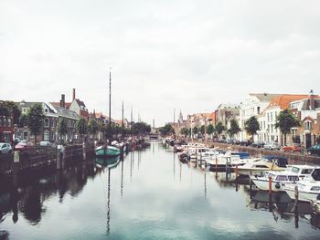 Boats moored in city against sky