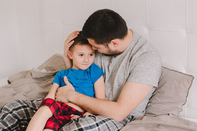Father and son sitting on bed at home