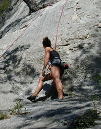 Low angle view of woman climbing on rock