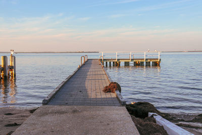 Pier over sea against sky during sunrise