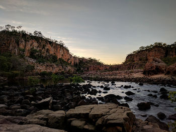 Rocks by sea against sky during sunset