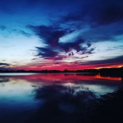 Scenic view of lake against dramatic sky during sunset