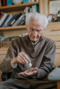 Senior man using hand sanitizer at home