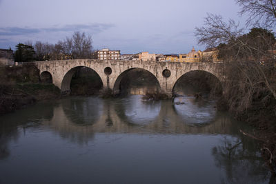 Arch bridge over river against sky