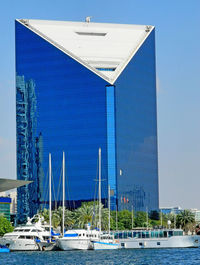 Modern building by sea against clear blue sky