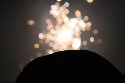 Defocused image of illuminated lights against sky at night