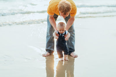 Full length of father and son at sea shore