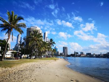 Scenic view of beach by buildings against blue sky