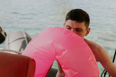 A young guy inflates a lifebuoy while sitting in a boat.