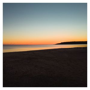 Scenic view of beach against clear sky during sunset