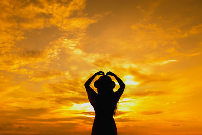 Silhouette person against orange sunset sky