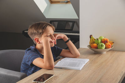 Boy sitting on table at home