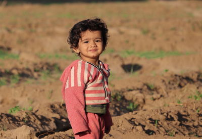 A closeup portrait photo of beautiful hindu little male boy standing in garden at sunset. 