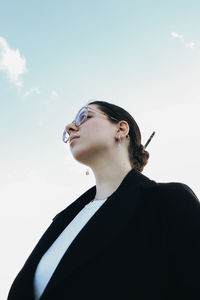 Low angle view of young woman against sky