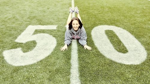 High angle portrait of woman lying on american football field