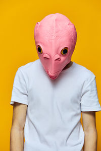 Close-up of man wearing mask against yellow background