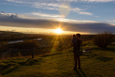 Full length of woman standing on field against sky during sunset