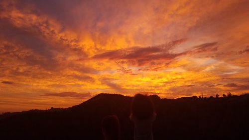 Silhouette people standing against orange sky