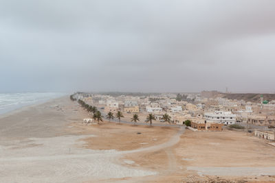 Scenic view of beach by buildings against sky