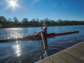 Happy young woman rowing on moselle river in morning