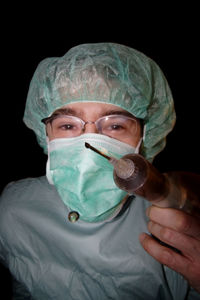 Portrait of young man holding hair over black background