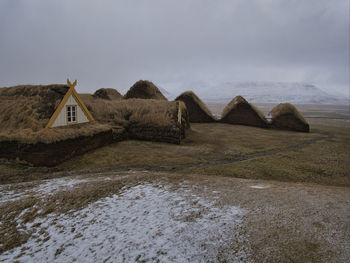 Built structure on land by sea against sky