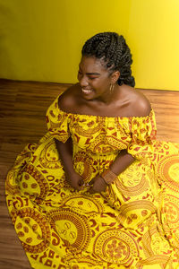 Young woman wearing colorful long clothes over yellow background. natural expression.