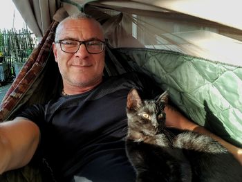 Portrait of man sitting with cat in tent 