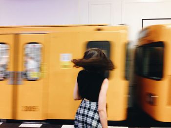 Rear view of woman standing on train at railroad station