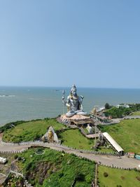 Scenic view of sea and lord shiva against clear sky