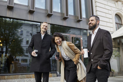 Smiling colleagues drinking coffee in street