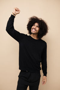 Young man gesturing against beige background