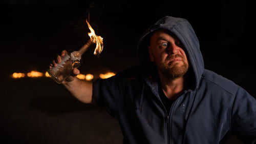 Portrait of young man holding sparkler at night