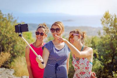 Woman taking selfie with friends against sky