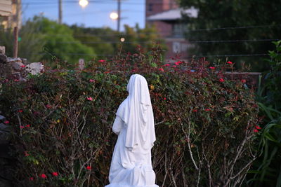 Close-up of woman standing by flowering plants on field