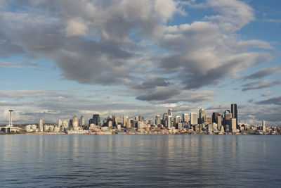 Sea by buildings in city against sky